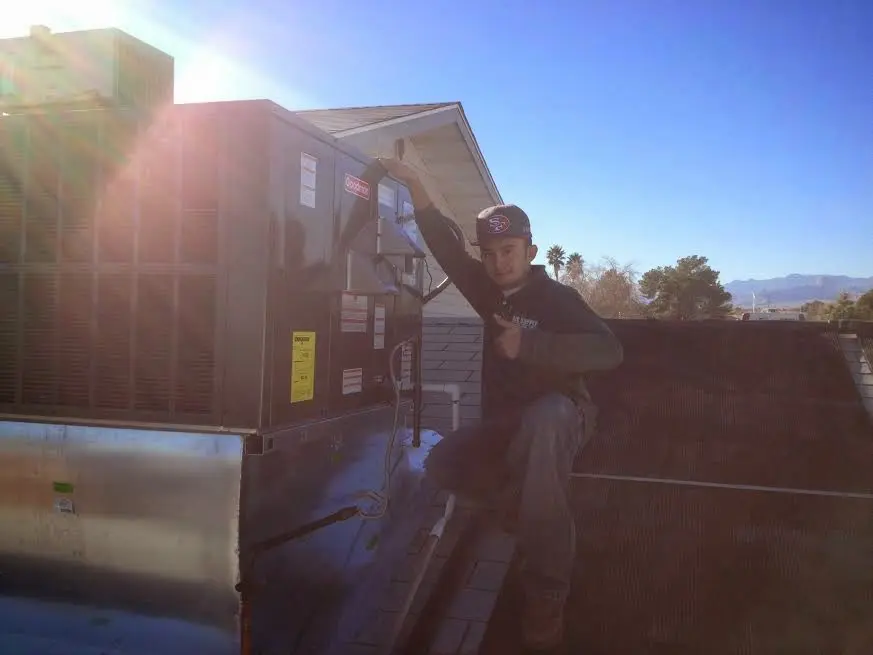 HVAC technician performing Air Duct Cleaning on a rooftop unit in Belterra